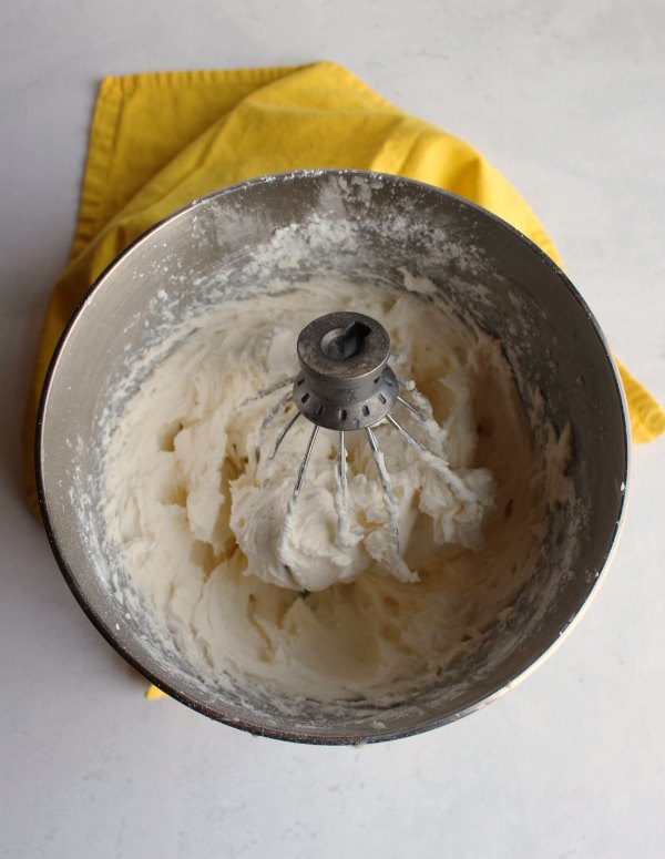 Mixer bowl of fluffy yellow sweetened condensed milk frosting ready to use.