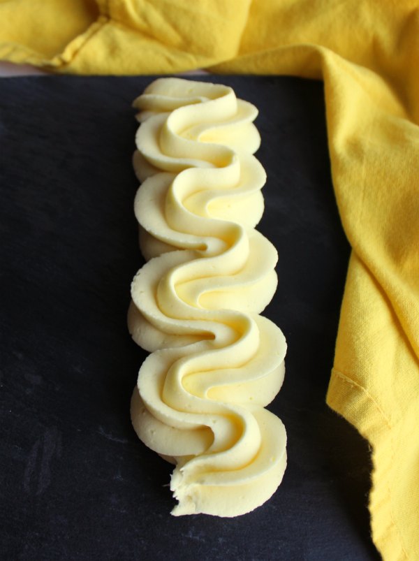 swirl of piped lemon buttercream on slate background. 
