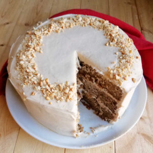 layered applesauce cake with soft and creamy caramel cream cheese frosting and a big slice missing showing the layers.