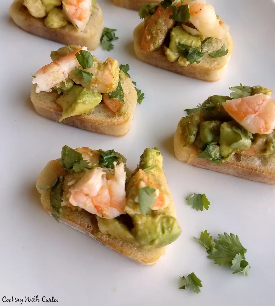 avocado and shrimp mixture on top of baguette slices with cilantro.