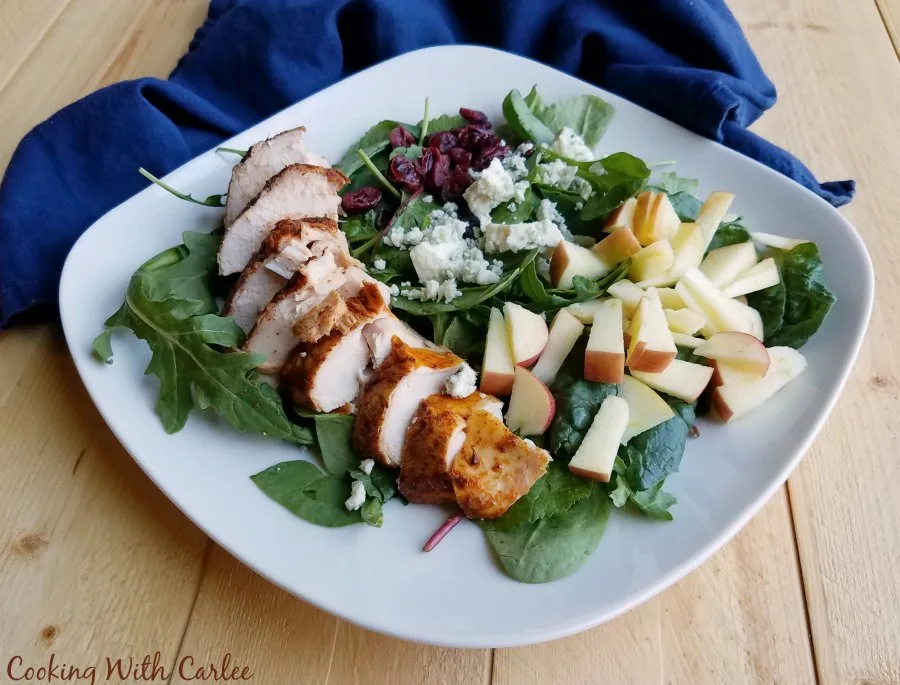 square plate with greens, smoked chicken, apples, cheese and more.