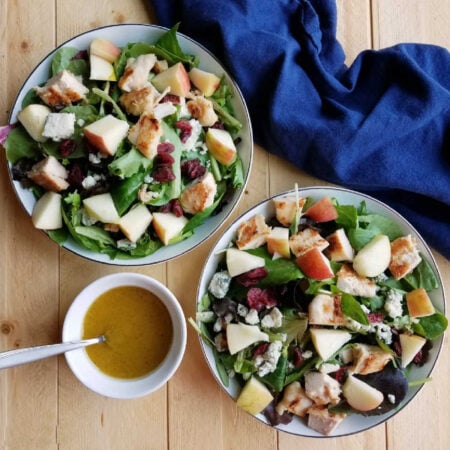 bowls of salad with chicken, cranberries, cheese, apples and homemade salad dressing.