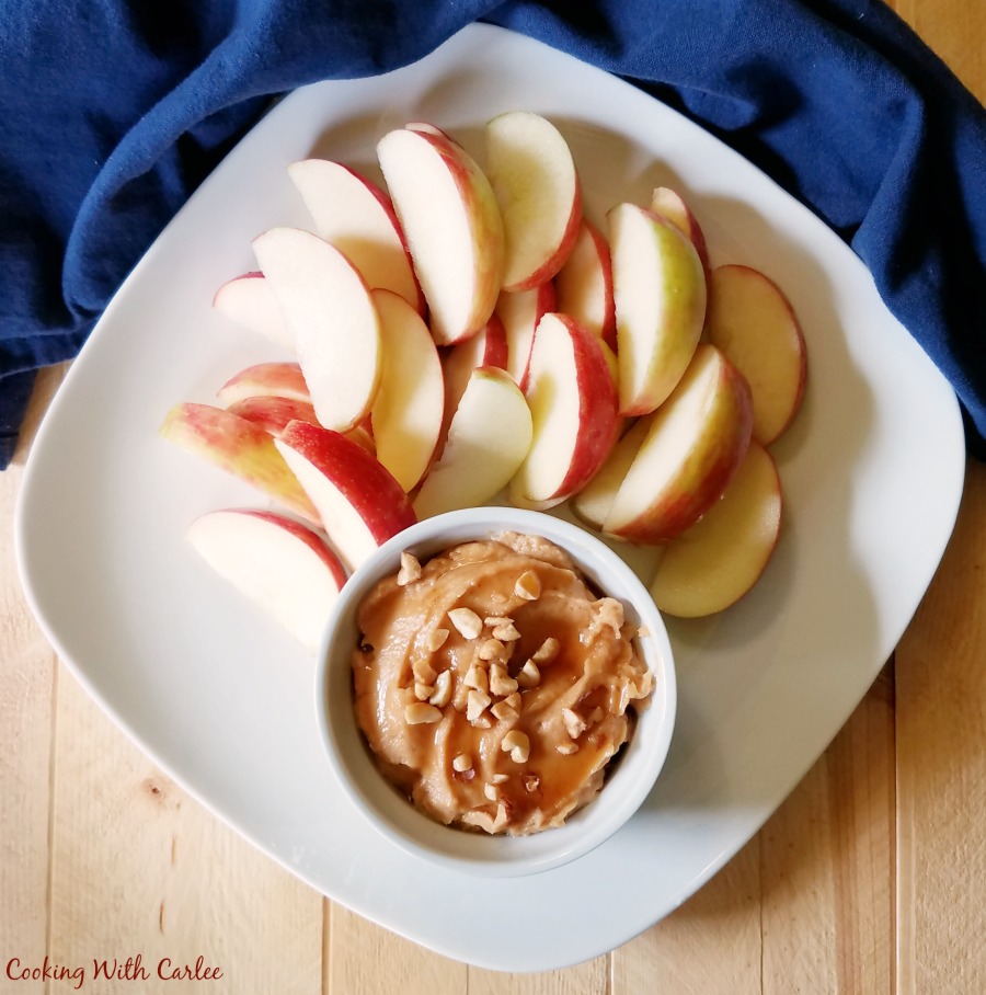 looking down at a plate of sliced apples and a ramekin of peanut butter yogurt fruit dip.