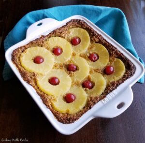 square pan filled with baked oatmeal topped with pineapple and cherries.