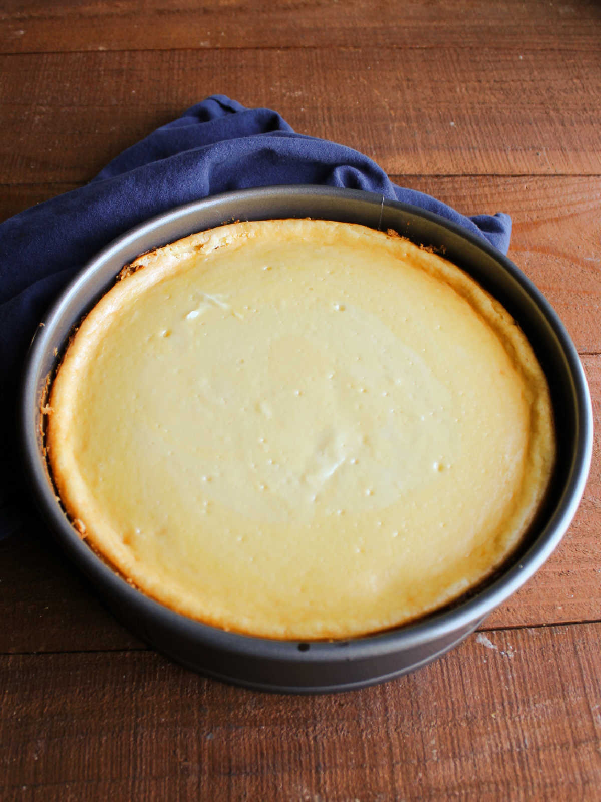 Baked cheesecake that has cooled slightly showing no crack and smooth finish.