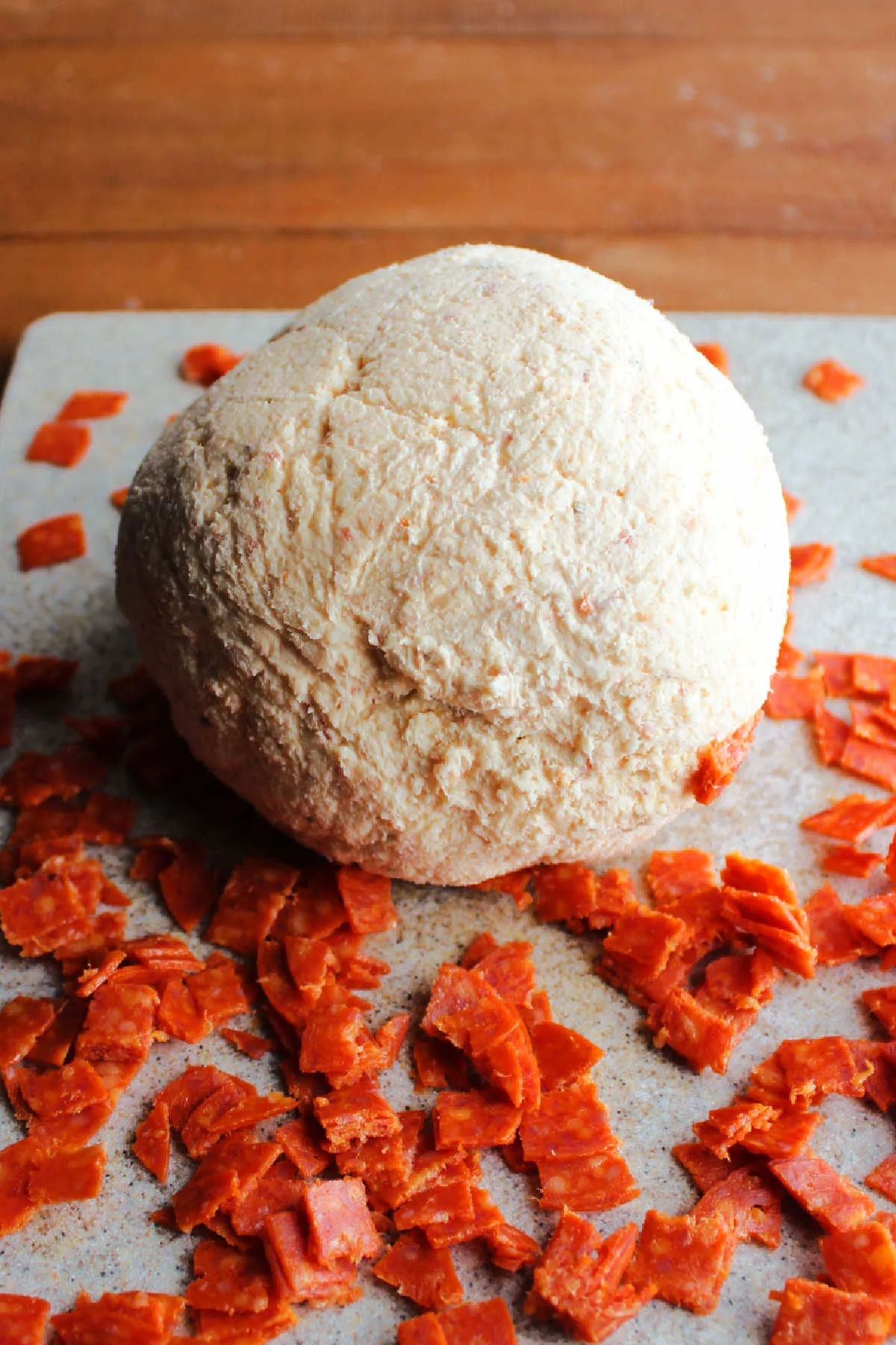 Rolling cheese ball around in pieces of pepperoni.