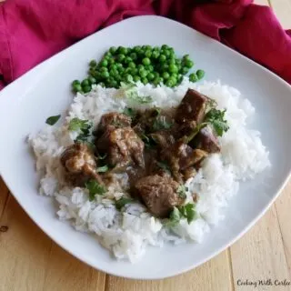 dinner plate with lamb curry and green peas.