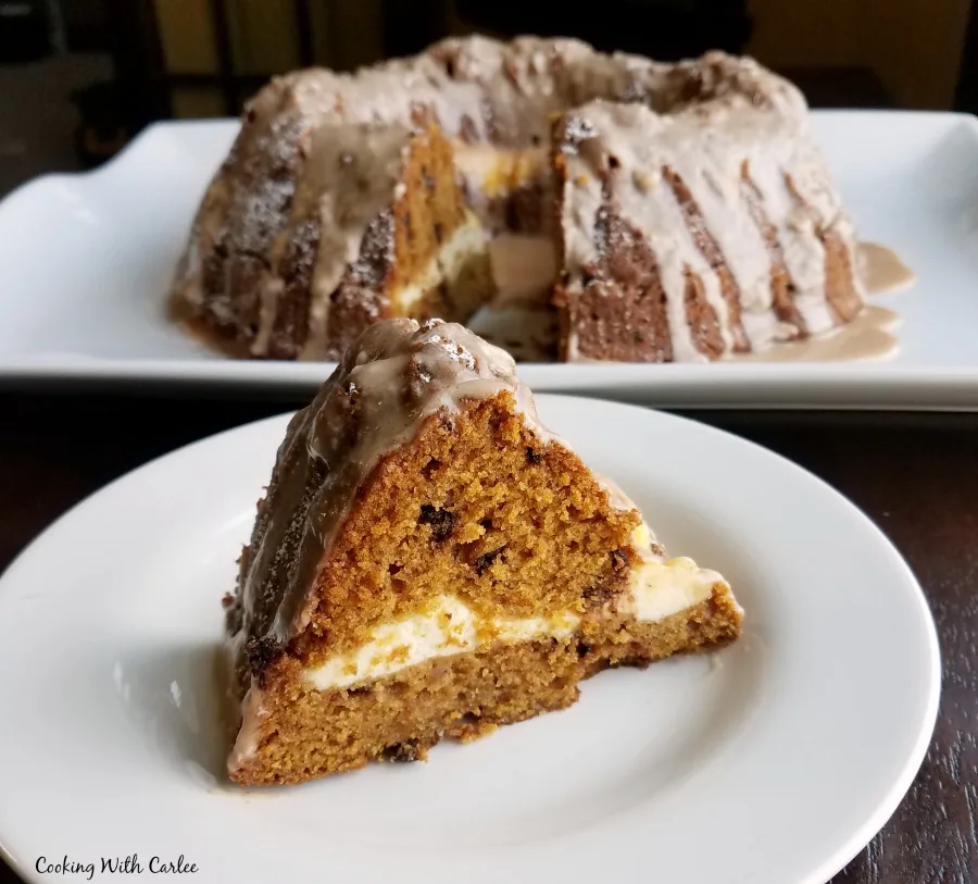Slice of pumpkin chocolate chip bundt cake with ribbon of cream cheese down the middle.