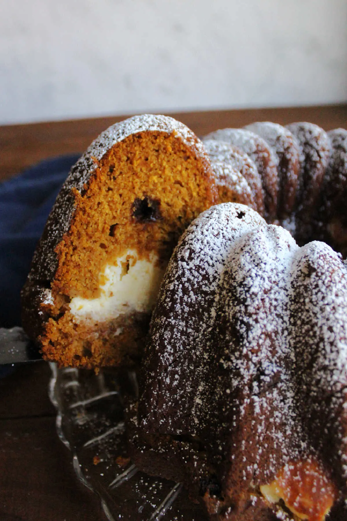 Lifting slice of cream cheese filled pumpkin bundt cake out of the cake to be served.
