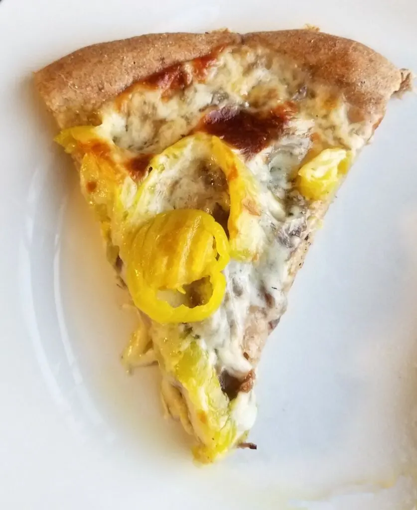 slice of Italian beef pizza with peppers and golden cheese ready to eat.