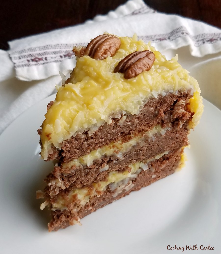 slice of german chocolate cake with golden coconut frosting and pecan halves