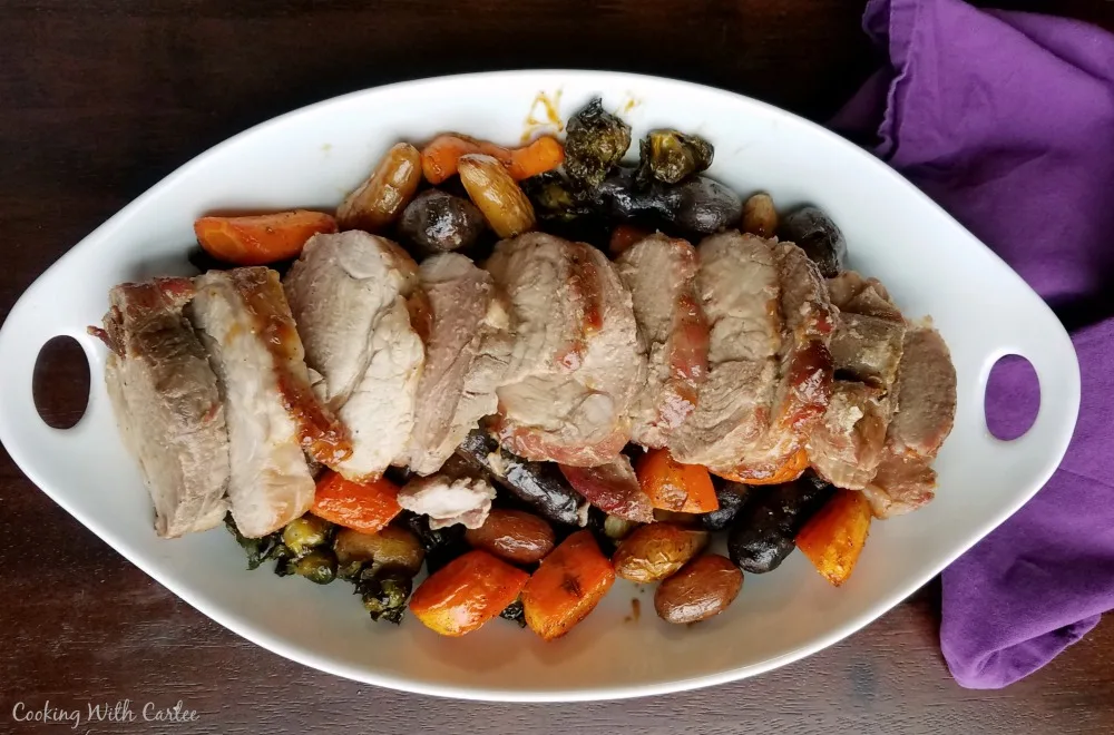 serving dish filled with vegetables and slices of pork roast