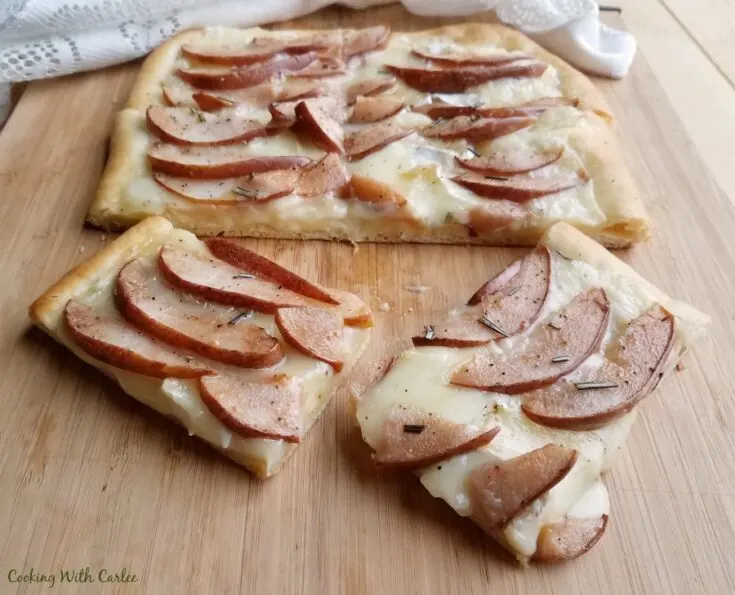 Slices of pear and brie flatbread on cutting board, ready to eat.