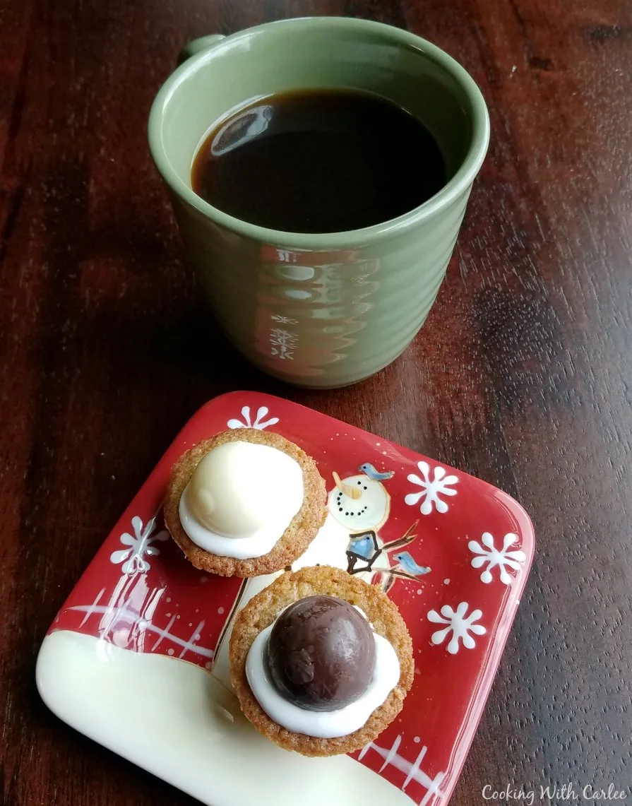 Small plate with a couple of cookie cups next to a mug of coffee.