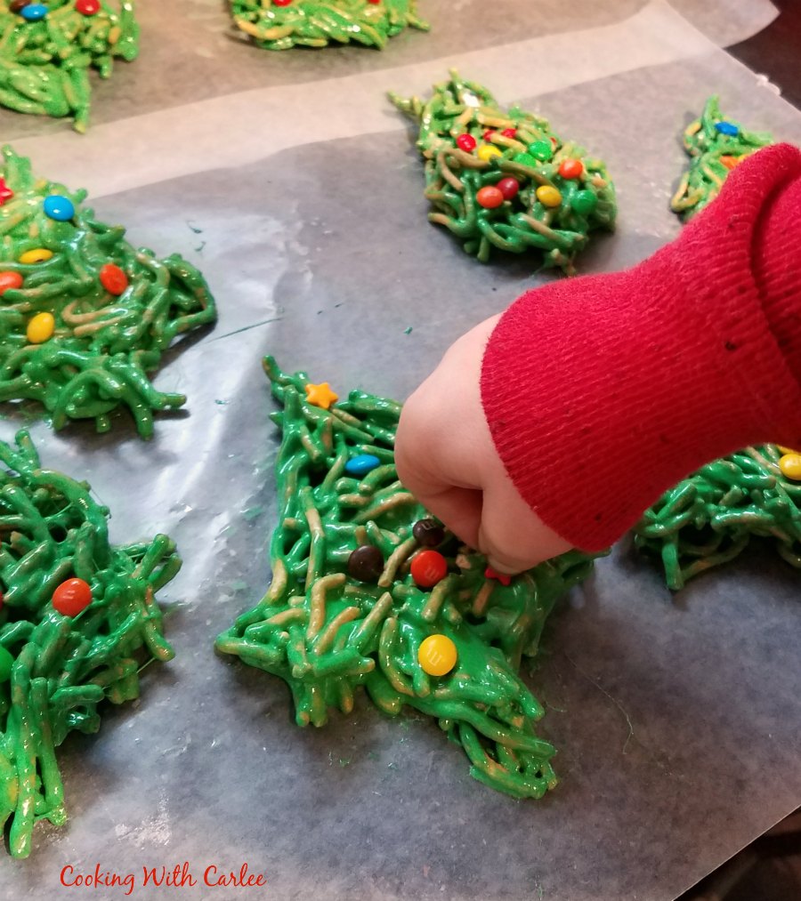 child's hand decorating no bake Christmas tree cookies.