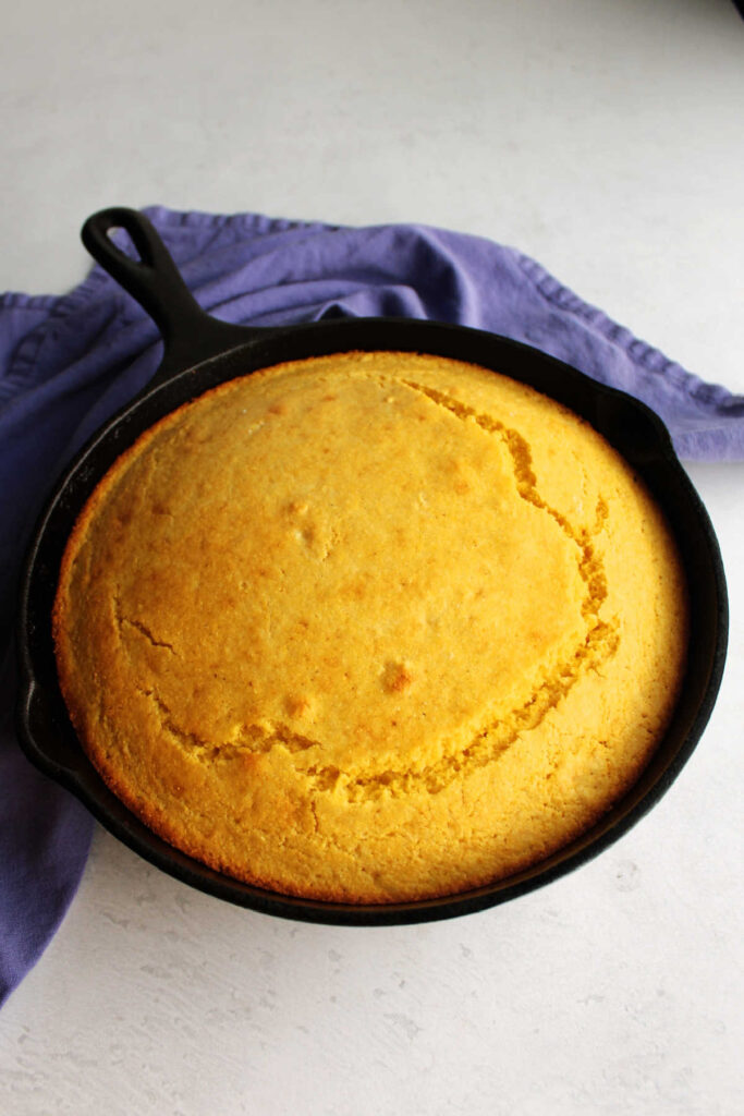 Cast iron skillet filled with yellow cornbread straight from the oven.
