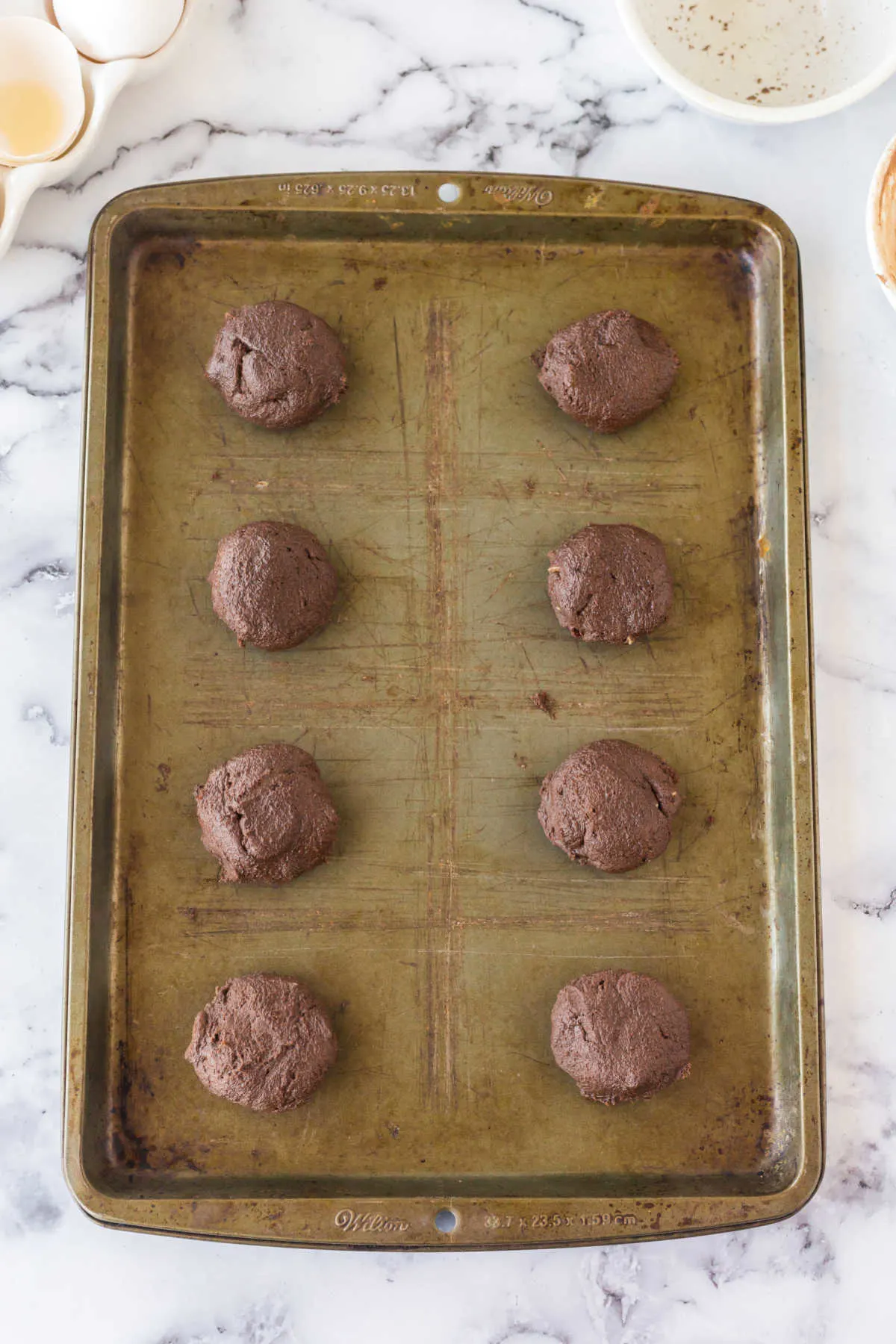 Balls of chocolate cookie dough on baking sheet, ready to go in the oven.