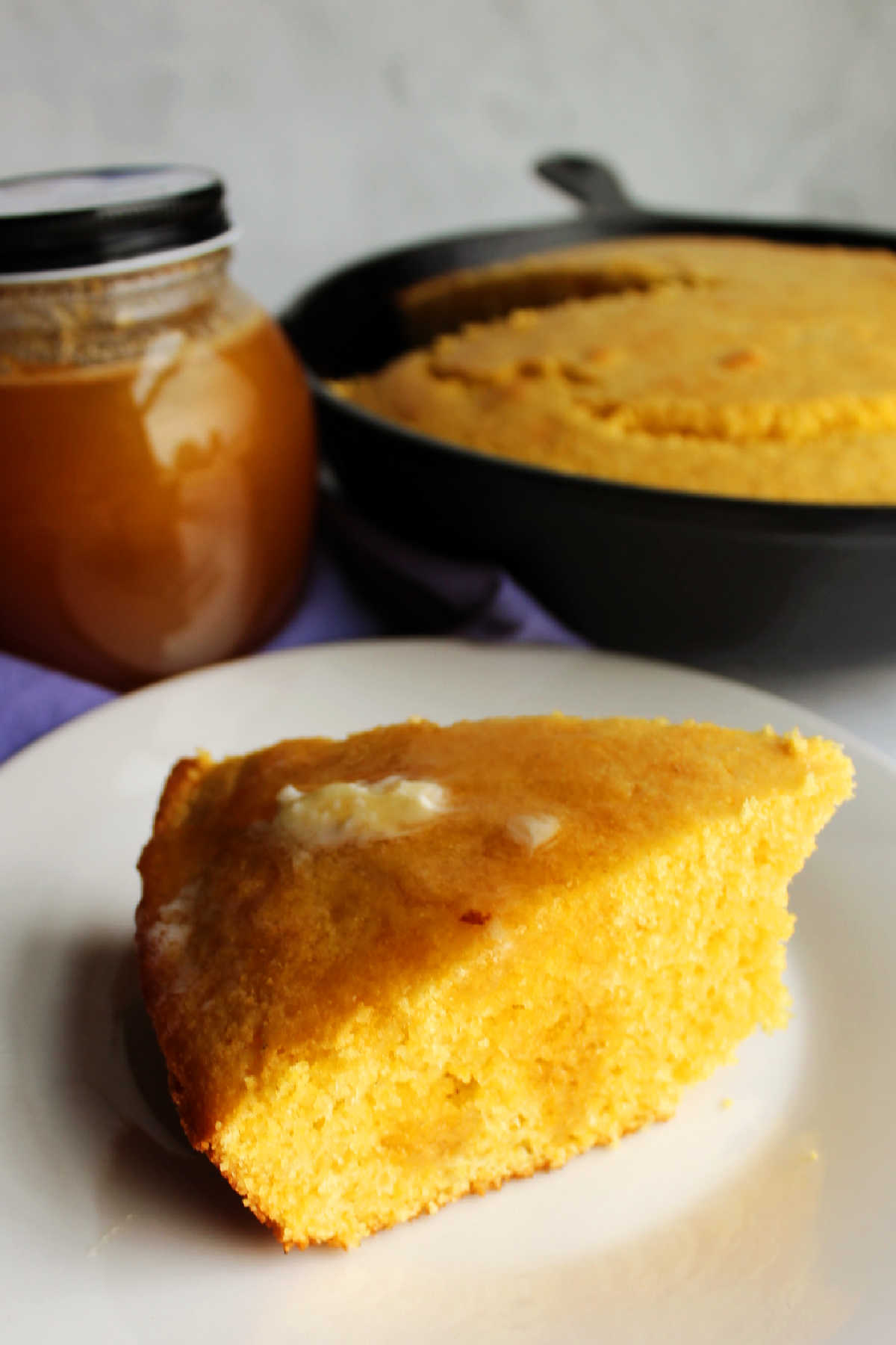 Slice of cornbread with honey and butter on top.