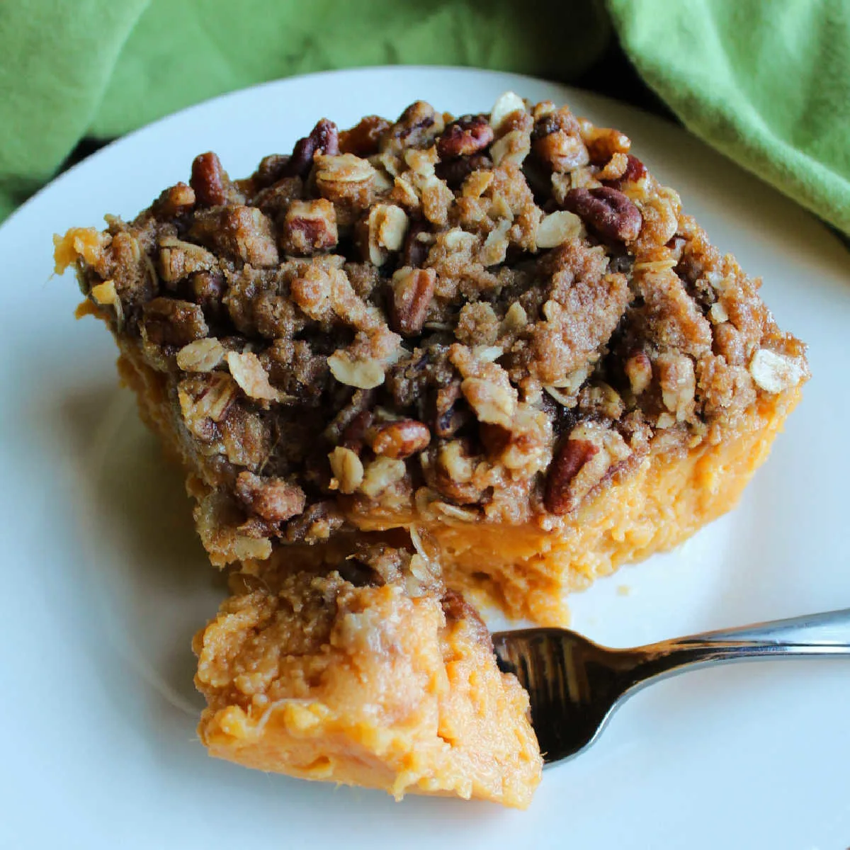 Forkful of maple sweet potato casserole topped with oats, pecans and brown sugar ready to eat.