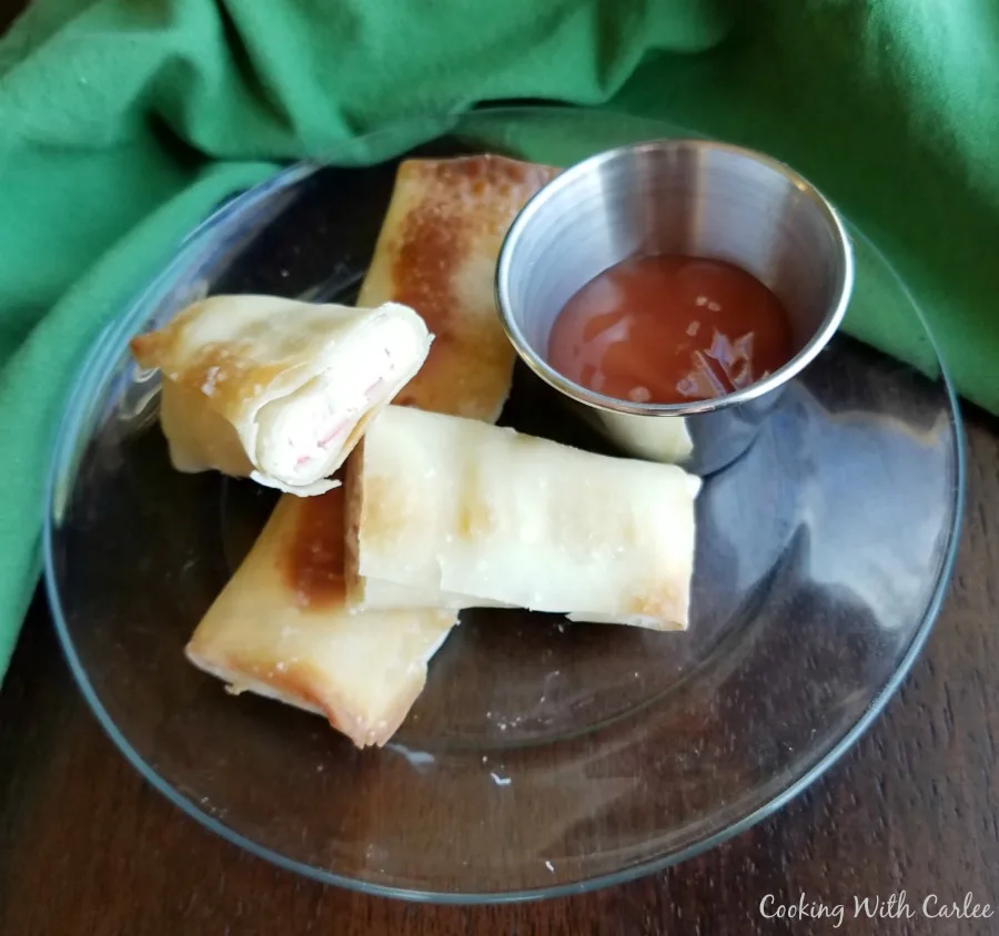 crab rangoon egg rolls with small container of sweet and sour sauce.