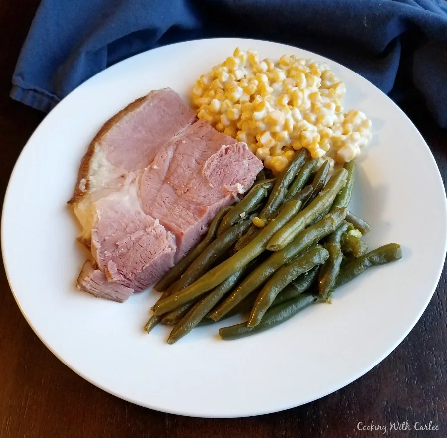plate with ham, green beans and creamed corn on it.