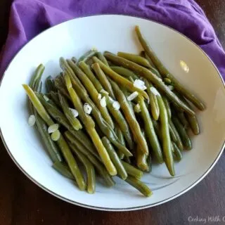 Bowl of garlic green beans with soy sauce and green onions.