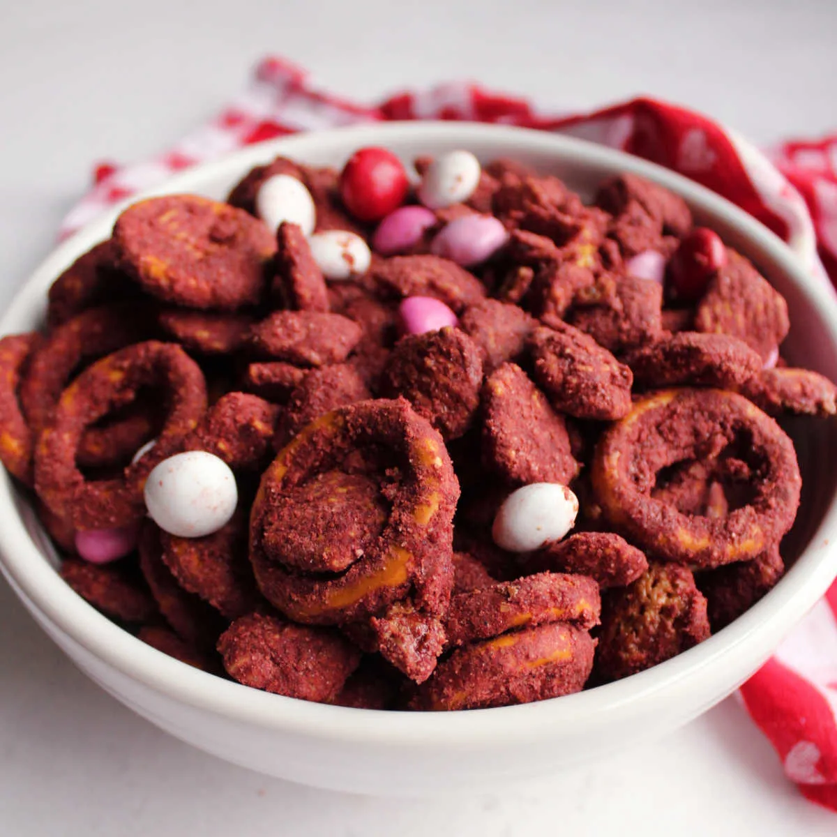 bowl of red velvet muddy buddies with pretzels and candies