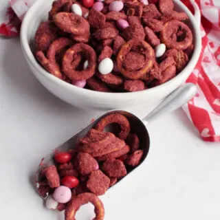 scoop full of red velvet puppy chow with pretzels and candies