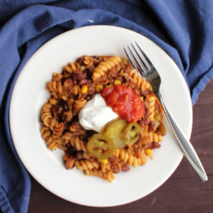 plate of taco pasta topped with sour cream salsa and jalapenos.