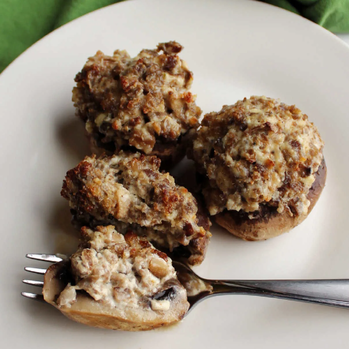 Plate of stuffed mushrooms filled with sausage and cream cheese mixture.