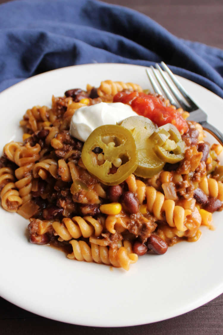 plate of taco pasta with rotini, taco meat, black beans etc. topped with sour cream and jalapenos.