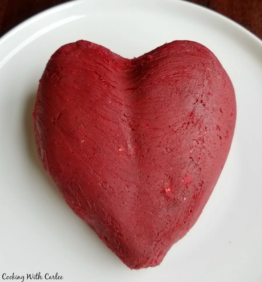 red velvet cheese ball hand shaped into a heart shape, ready to be coated in white chocolate