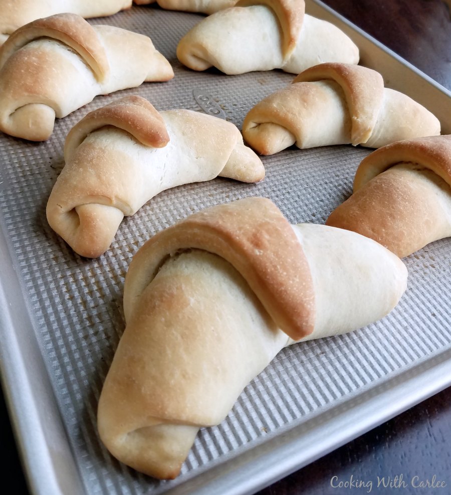 Golden baked crescent rolls on baking sheet fresh from the oven.