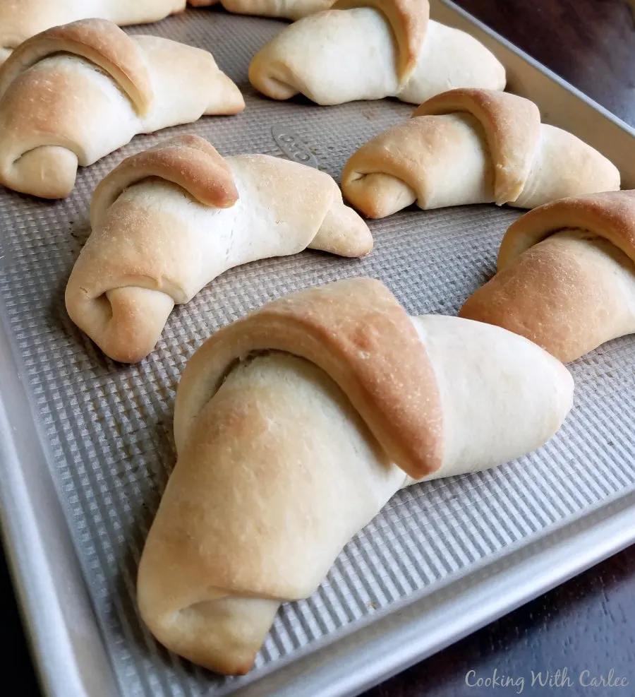 Golden baked crescent rolls on baking sheet fresh from the oven.