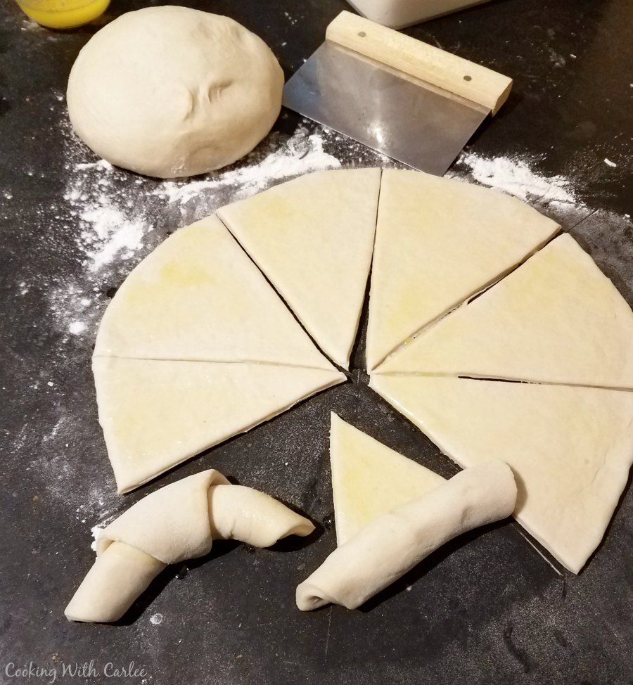 Sourdough crescent dough rolled out into a circle and cut into wedges with two rolled into crescent shapes.