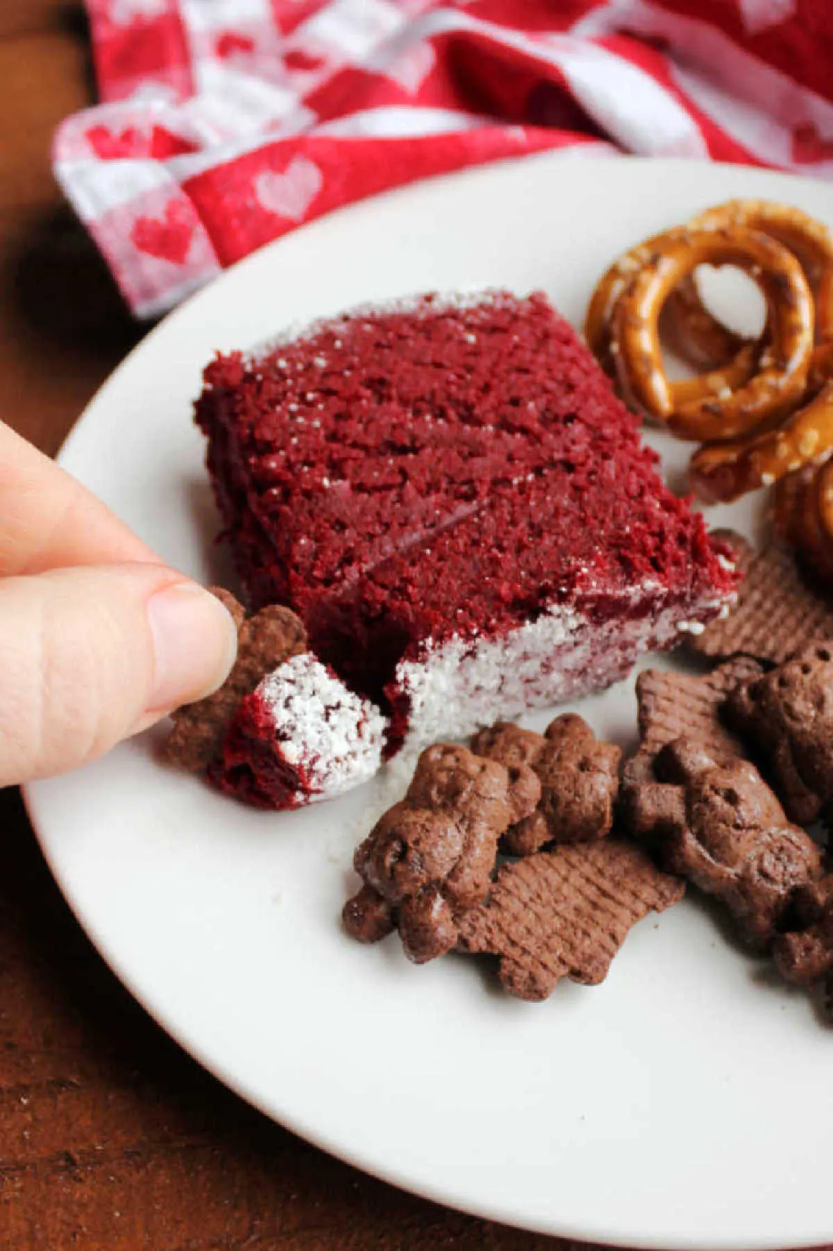 plate with helping of red velvet cheese ball, cookies and pretzels ready to eat.