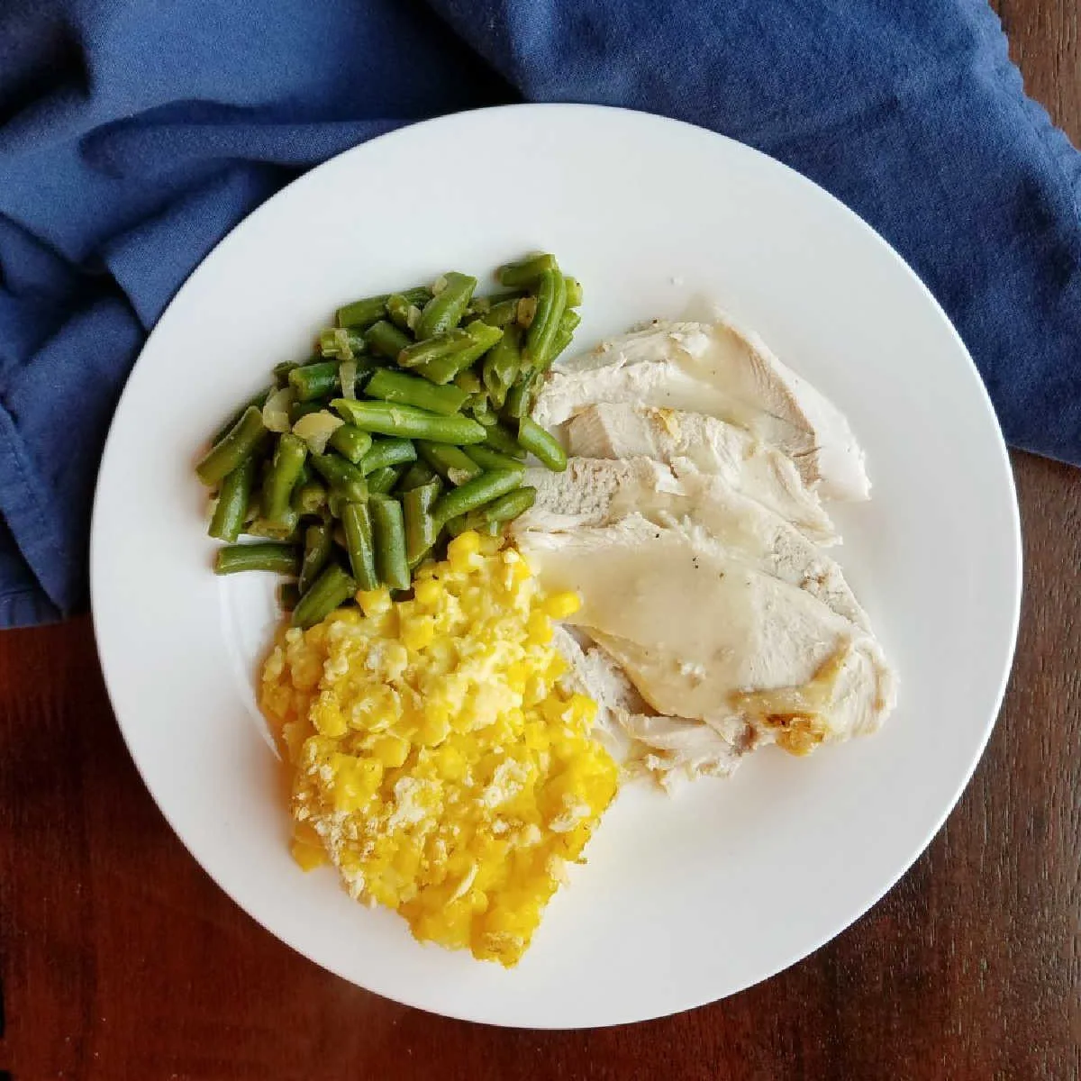 dinner plate with turkey, gravy, green beans and scalloped corn.