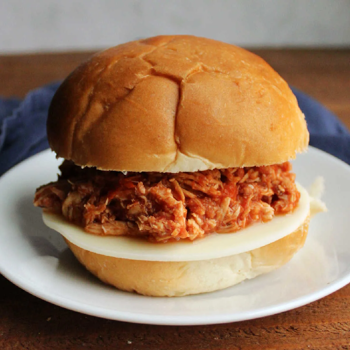 Sandwich made from bun, provolone cheese, and shredded marinara to make a tasty chicken parm sandwich with a crockpot filling.