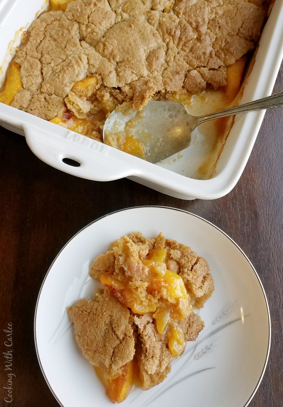serving of brown sugar peach cobbler on plate next to 9x13 pan with remaining dessert in it.