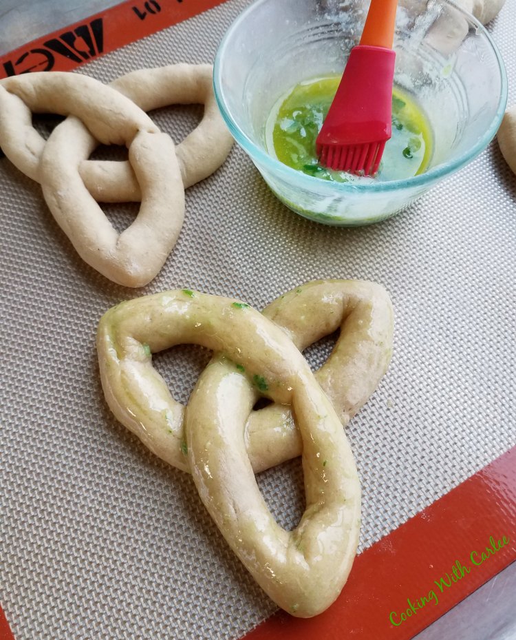 brushing celtic knot rolls with herb butter.