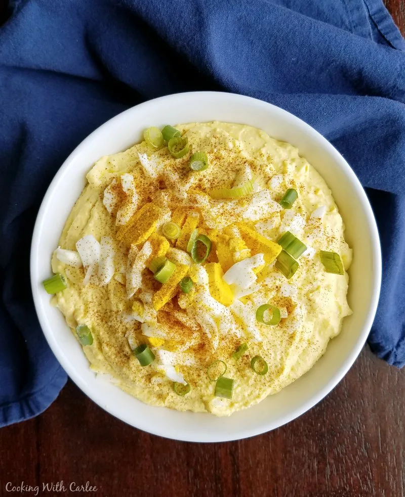 big bowl of deviled egg dip topped with chopped eggs, green onions and paprika.