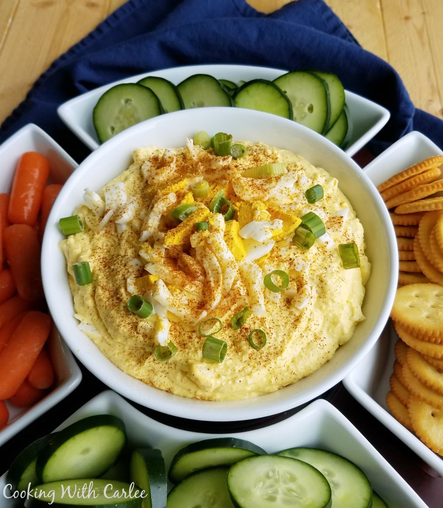 bowl of deviled egg dip with carrots, cucumbers and crackers for dipping