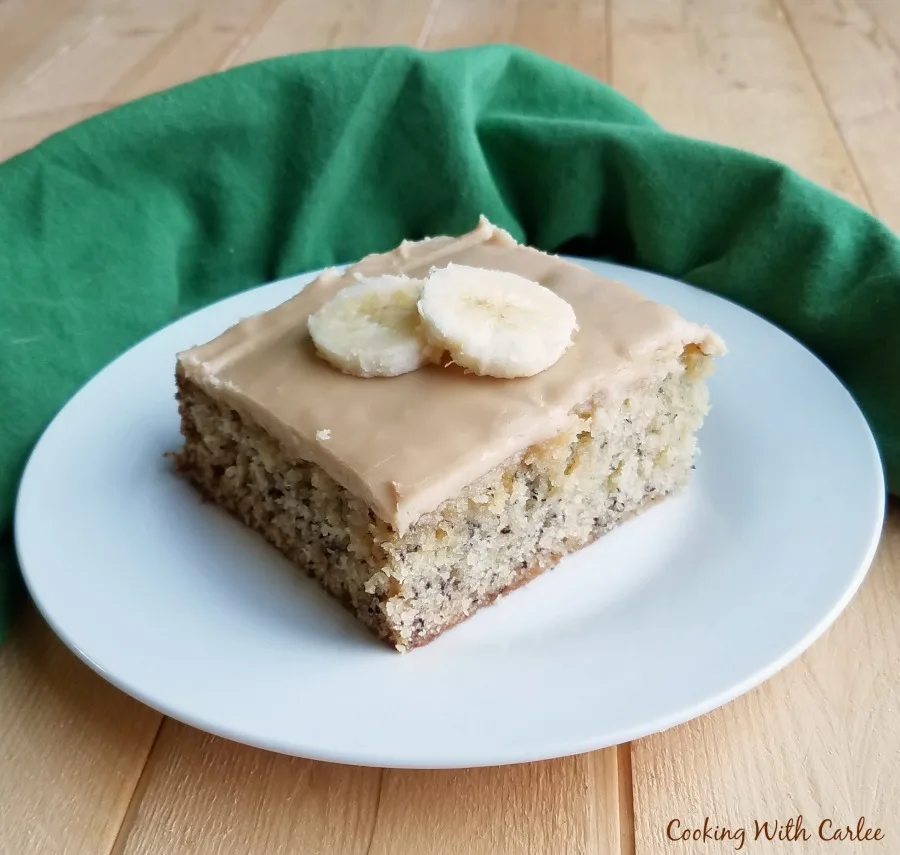 Slice of banana sheet cake with butterscotch frosting on top.