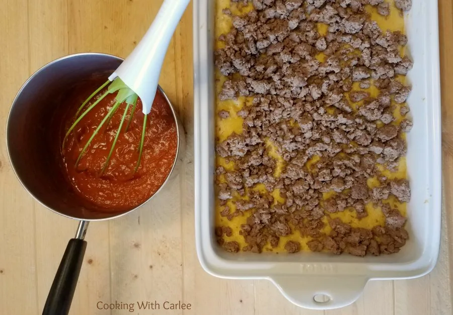 saucepan on enchilada sauce next to pan filled with corn mixture and ground meat.
