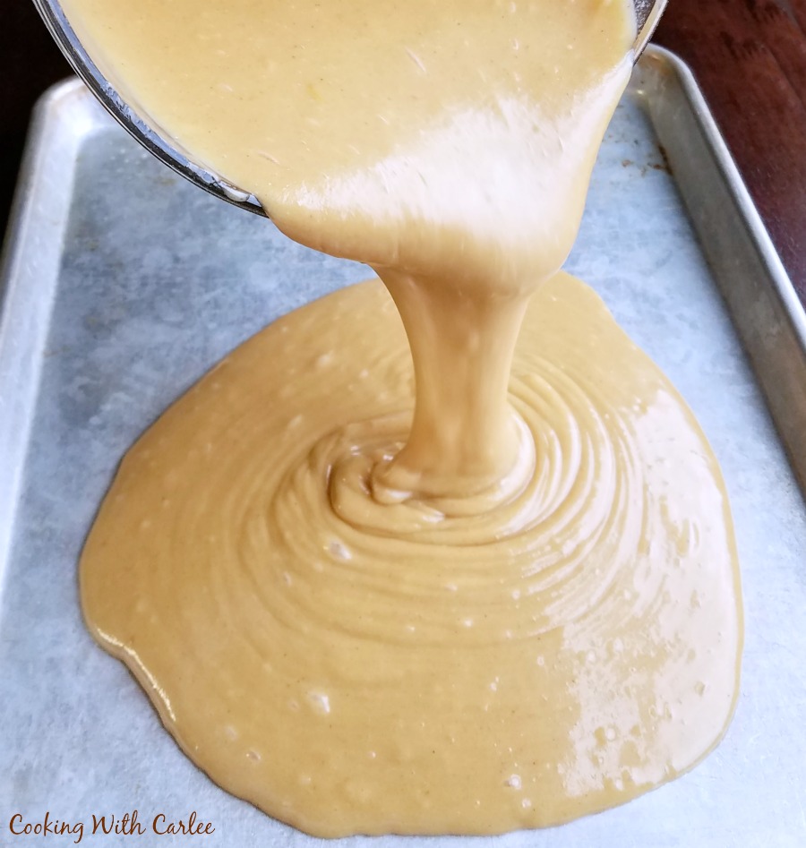 pouring peanut butter cake batter into sheet pan.