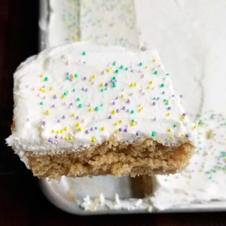 piece of frosted peanut butter sheet cake being lifted out of pan.