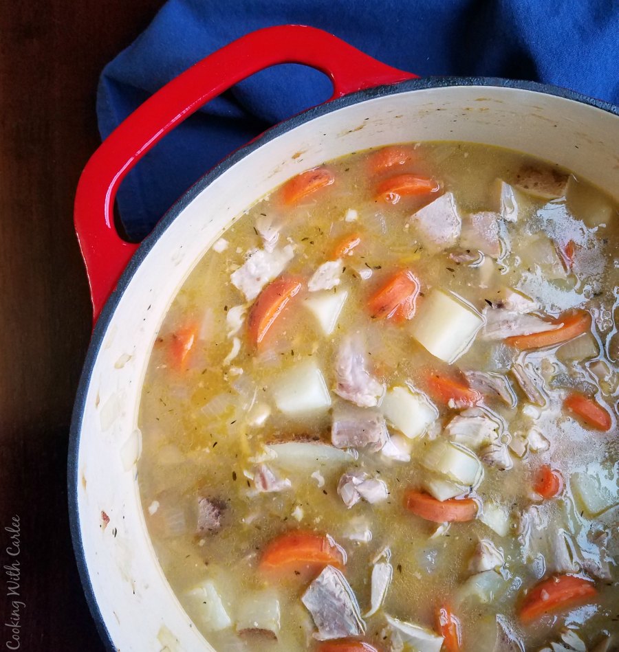 Red dutch oven filled with shortcut chicken stew with potatoes and carrots ready to eat. 