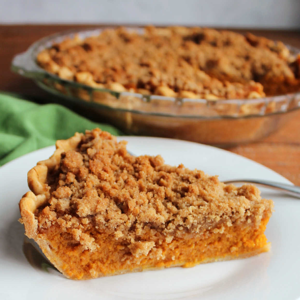 Slice of carrot pie with smooth orange filling topped with buttery crumble topping, ready to eat.