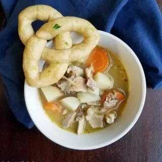 bowl of chicken stew with a trinity knot roll.