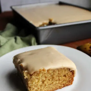Piece of moist banana cake topped with penuche icing, ready to eat.